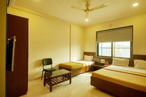 a hotel room with two beds and a chair at Sai Vidisha Palace in Shirdi