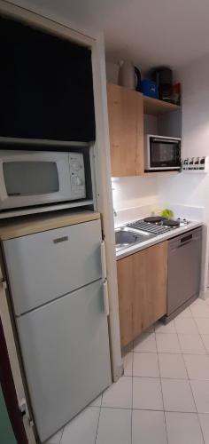 Il comprend une cuisine équipée d'un réfrigérateur blanc et d'une cuisinière. dans l'établissement Studio 25m2/côté couchant-plages & commerces, à La Grande Motte