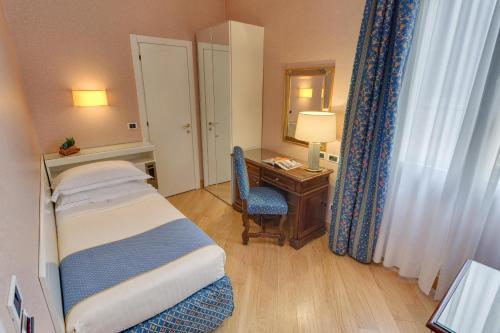 a hotel room with a bed and a desk with a mirror at Rivoli Boutique Hotel in Florence