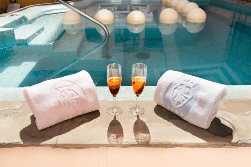 two glasses of wine and towels next to a swimming pool at Rivoli Boutique Hotel in Florence