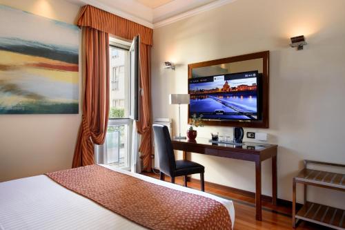 a hotel room with a bed and a desk and a tv at Grand Hotel Adriatico in Florence