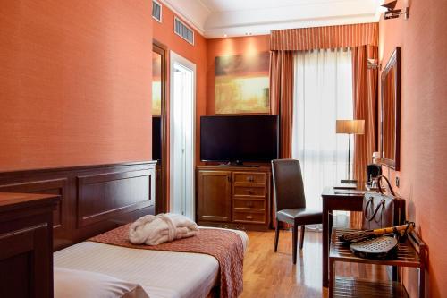 a bedroom with a bed and a tv and a desk at Grand Hotel Adriatico in Florence