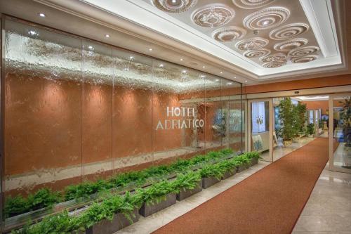 a hotel entrance with a row of plants on a wall at Grand Hotel Adriatico in Florence