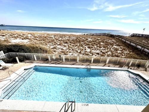 a swimming pool with a beach in the background at Sunshine Daydream condo in Navarre