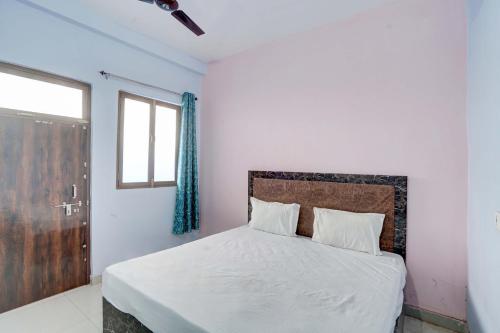 a bedroom with a bed with white sheets and a window at OYO SM GALAXY in Kānpur