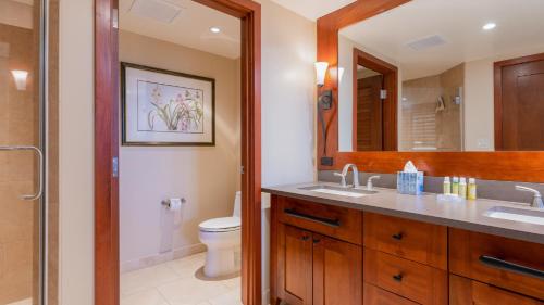 a bathroom with a sink and a toilet and a mirror at Ko Olina Beach Villas B701 in Kapolei