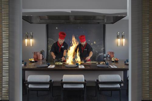 two chefs preparing food in a kitchen with flames at Marriott Vacation Club at Surfers Paradise in Gold Coast