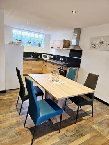 eine Küche mit einem Holztisch und blauen Stühlen in der Unterkunft appartement cosy à seloncourt in Seloncourt