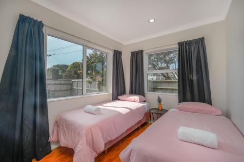 two beds in a room with a window at Large House. Convenient Location. in Auckland