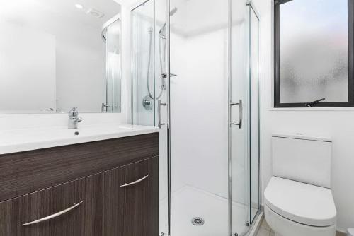 a bathroom with a toilet and a glass shower at Large House. Convenient Location. in Auckland