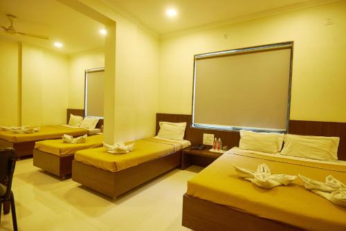 a room with three beds and a large mirror at Sai Vidisha Palace in Shirdi
