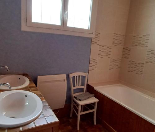 a bathroom with a sink and a tub and a chair at Appartement Daniel in Lamoura