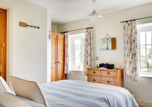 a bedroom with a bed and a dresser and a window at Coastguard Cottage in Paignton