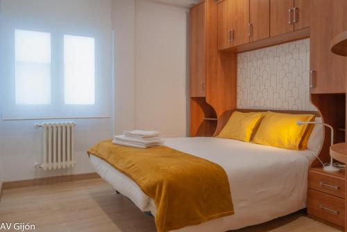 希洪的住宿－AV Gijón Palencia 3，一间卧室配有一张带黄色枕头的大床