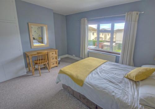 1 dormitorio con cama, escritorio y ventana en Dalmose, en Seaton