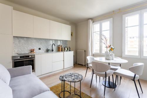 a kitchen with white cabinets and a table and chairs at The Carla Suite Eiffel Tower View in Paris