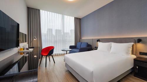 a hotel room with a white bed and a red chair at Holiday Inn Express Taichung Park by IHG in Taichung