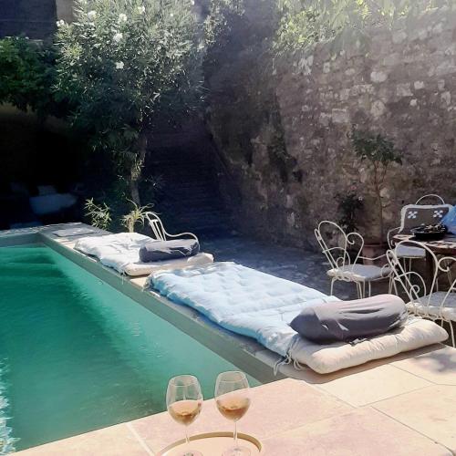 - une piscine avec 2 matelas et 2 verres de vin dans l'établissement Maison typique provençale - Piscine privée - Clim, à Collorgues