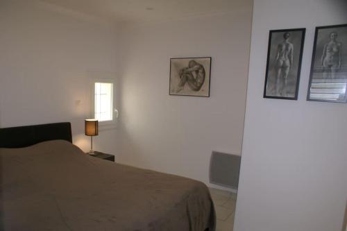 une chambre avec un lit et des tableaux au mur dans l'établissement Villa 68, port nature au village naturiste, au Cap d'Agde