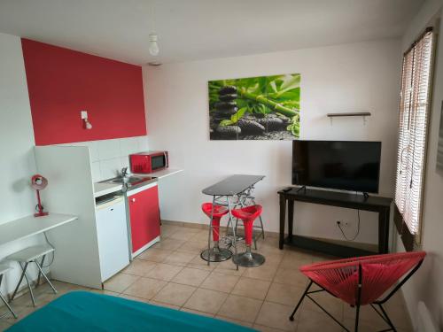 a kitchen with red cabinets and a table and chairs at Hébergements Sylvain in Neuilly-lʼÉvêque