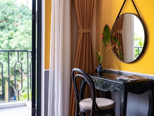 a room with a table and a mirror and a balcony at Sen Village Hoi An in Hoi An