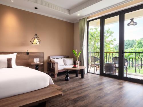 a bedroom with a bed and a balcony at Sen Village Hoi An in Hoi An