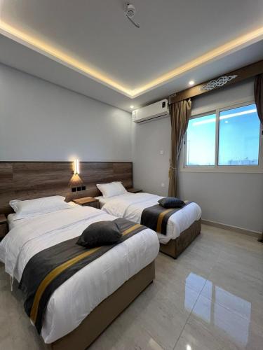 a hotel room with two beds and a window at بارك بلس للشقق المخدومة in AR Rummanah