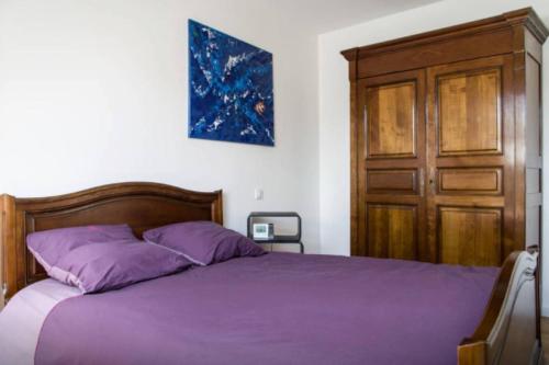 a bedroom with a purple bed and a wooden door at MAISON CREUZIER - Vichy à 5min - Jardin - BBQ - Calme in Creuzier-le-Vieux