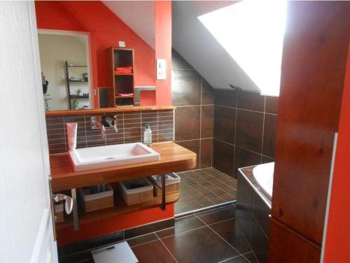 La salle de bains est pourvue d'un lavabo et d'un mur rouge. dans l'établissement MAISON CREUZIER - Vichy à 5min - Jardin - BBQ - Calme, à Creuzier-le-Vieux