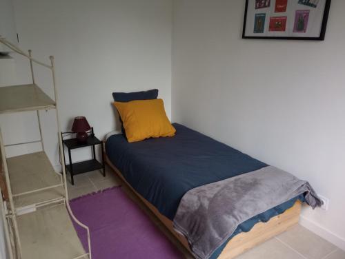uma cama com uma almofada amarela num quarto em La Cour Angot em Cormeilles