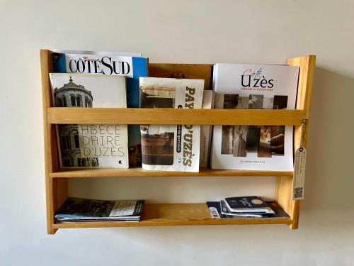 ein Bücherregal aus Holz mit Zeitschriften und Zeitungen in der Unterkunft La bohème place aux herbes in Uzès