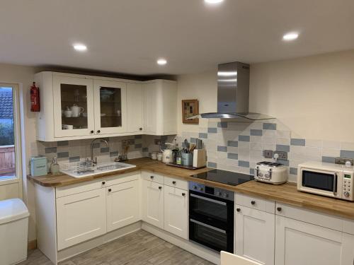 uma cozinha com armários brancos e um forno com placa de fogão em Locheil Apartment em Boat of Garten