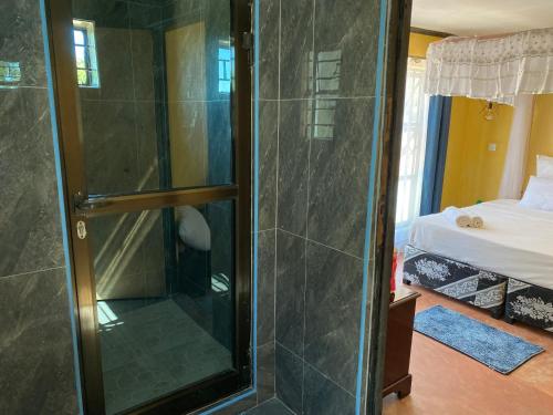 a shower with a glass door in a bedroom at Capricorn Lake Cottage in Cape Maclear