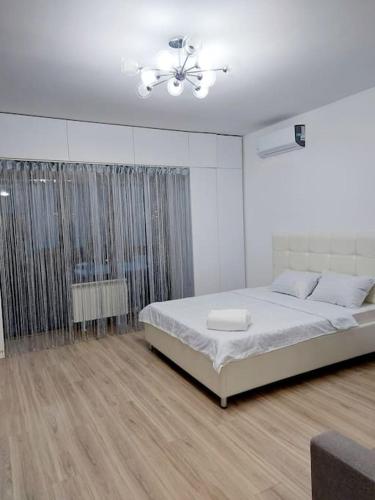 ein weißes Schlafzimmer mit einem Bett und einem Deckenventilator in der Unterkunft ЖК Novella in Almaty