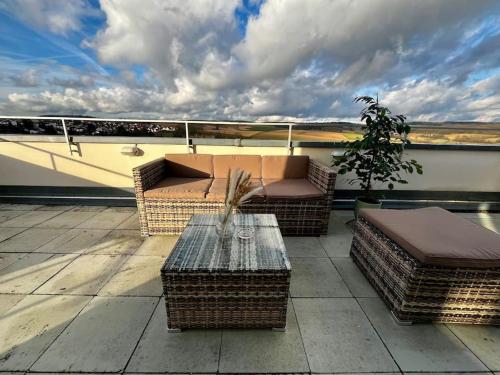 a patio with wicker furniture and a table on a roof at Charmante Penthouse - Nahe Badewelt - Hoffenheim Stadion in Sinsheim