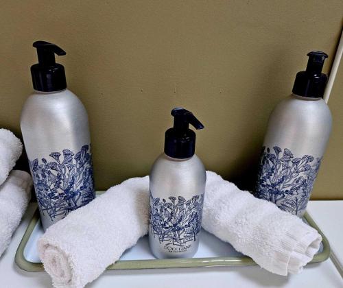 a group of three bottles on a shelf with towels at La Maison Grivolas Appartements et Maison d'hôtes in Avignon