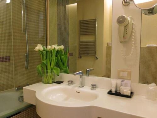 a bathroom with a sink with a vase of flowers at Best Western Plus Hotel Le Favaglie in Cornaredo