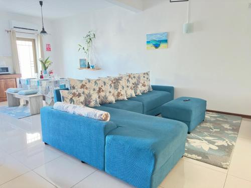 a living room with a blue couch and a table at Residence Le Point Choisy in Pointe aux Cannoniers