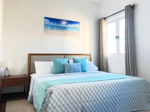 a bedroom with a bed with blue sheets and a window at Residence Le Point Choisy in Pointe aux Cannoniers