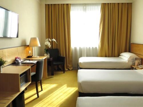 a hotel room with two beds and a desk at Best Western Plus Hotel Le Favaglie in Cornaredo