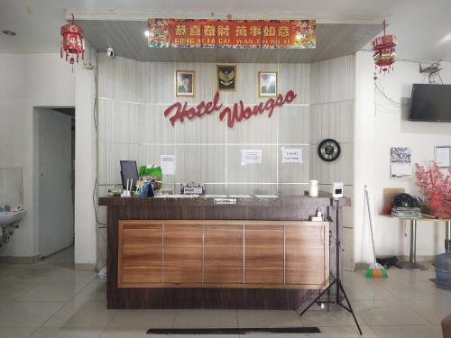 a restaurant with a counter with a sign on the wall at Capital O 93589 Hotel Wongso Syariah in Pangkal Pinang