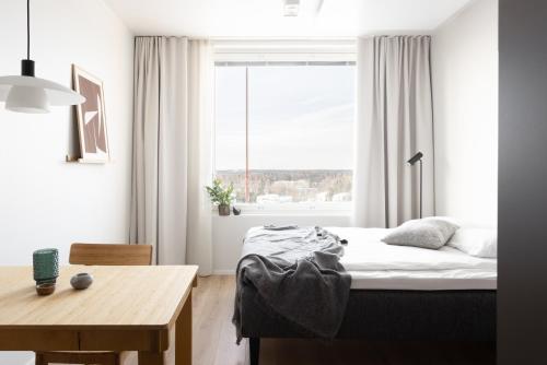 a bedroom with a bed and a table and a window at Noli Otaniemi in Espoo