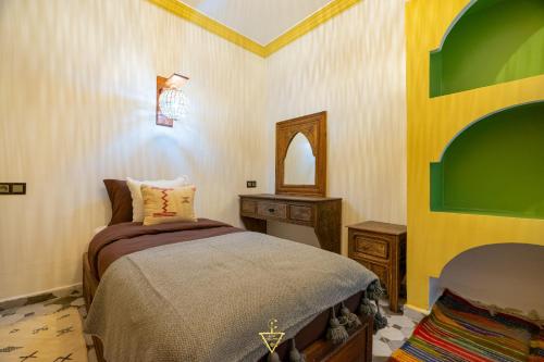 a bedroom with a bed and a table and a mirror at Riad Village in Imlil