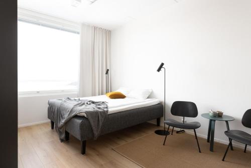 a bedroom with a bed and two chairs and a window at Noli Otaniemi in Espoo