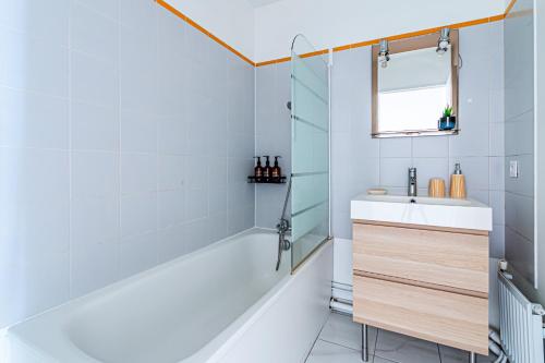 a bathroom with a tub and a sink and a mirror at Appart moderne tout confort La Clef d'Élancourt in Élancourt