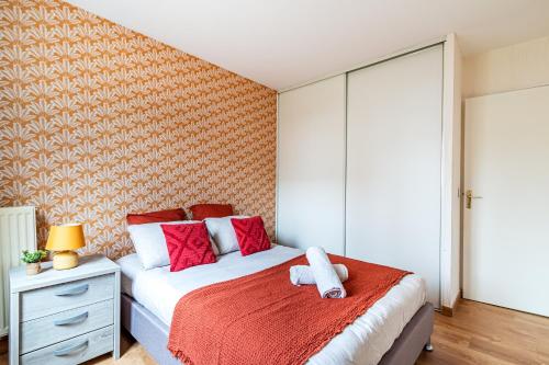 Appart moderne tout confort La Clef d'Élancourt في إيلانكورت: غرفة نوم بسرير ومخدات حمراء