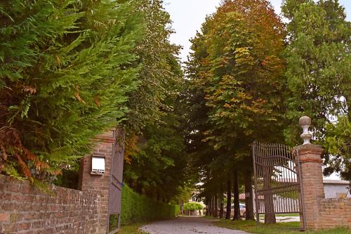 a brick fence with a gate in front of trees at La Tenuta Va Oltre in Bovolenta