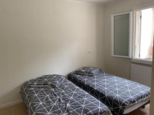 deux lits jumeaux dans une chambre avec fenêtre dans l'établissement Maison agréable à La Teste-de-Buch, à La Teste-de-Buch