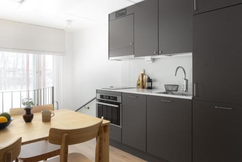 a kitchen with gray cabinets and a wooden table at Noli Otaniemi in Espoo