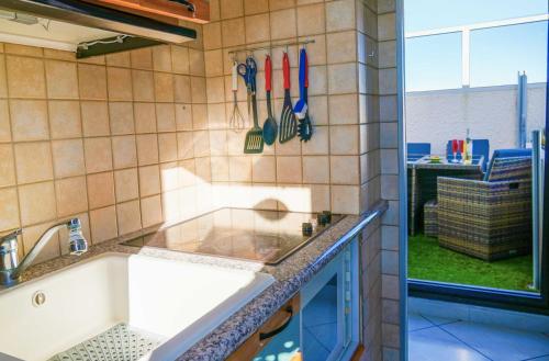 - une cuisine avec évier et ustensiles sur le mur dans l'établissement Chez Jo, au Barcarès